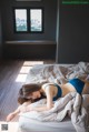 A woman laying on a bed in a blue bikini.