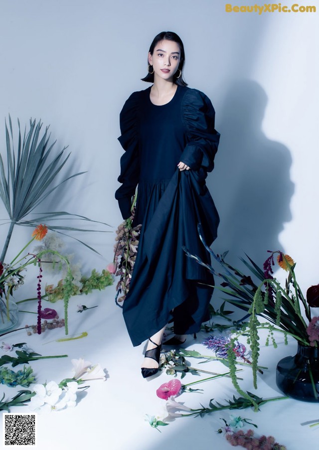 A woman standing in front of a bunch of flowers.