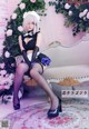 A woman in a maid outfit sitting on a couch.