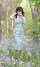A woman in a blue dress standing in a field of flowers.
