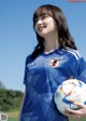 A woman holding a soccer ball on a field.