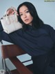 A woman sitting on a chair holding a white bag.