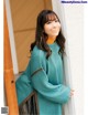 a woman wearing a green sweater and a black skirt