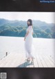 A woman in a white dress standing on a wooden dock.